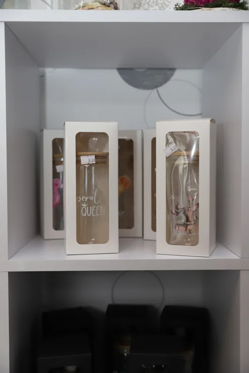Regal mit dekorativen Flaschen in Geschenkverpackungen