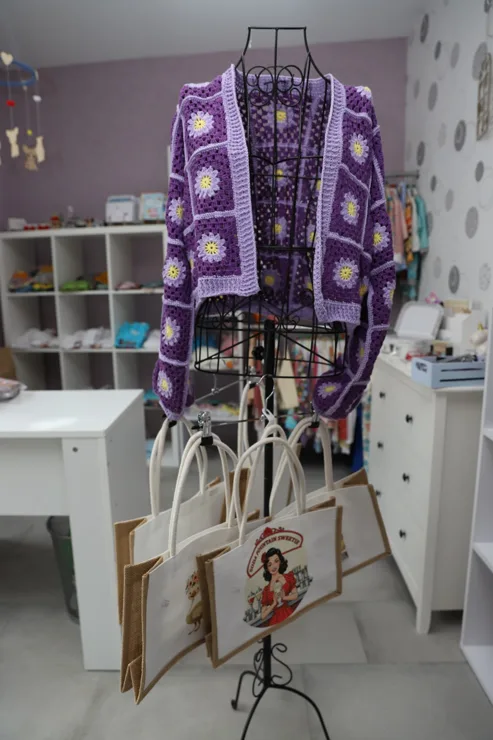 Violette Häkeljacke und bedruckte Taschen im Laden